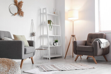 Interior of modern living room with comfortable armchairs and shelving unit