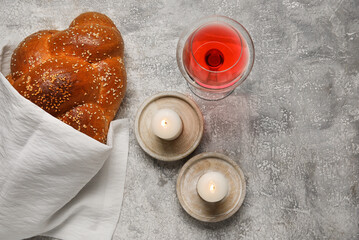 Fototapeta na wymiar Traditional challah bread with glass of wine and candles on grunge background. Shabbat Shalom