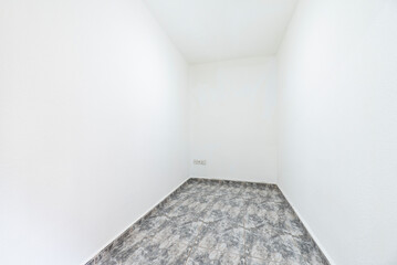 Empty room with gray stoneware floors, matching baseboards and white painted walls and nothing else