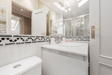 Bathroom with white furniture, white resin sink, frameless mirror and white tiles with border, sink on white marble countertop and shower cabin