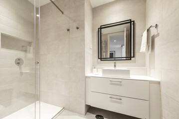 bathroom with white cabinets, shower stall with sliding glass screen, square wall mirror and cream tiling