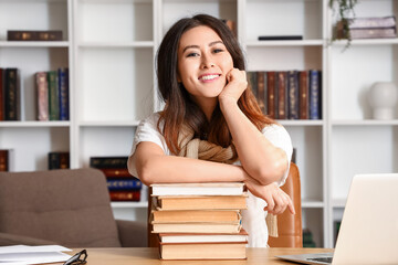 Young Asian tutor with books sitting at home