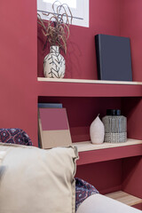 Lateral work shelf integrated in a wall niche painted in wine color with decorative objects to that of a fabric sofa