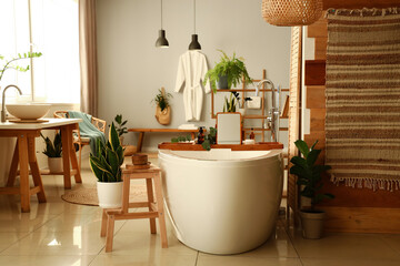 Interior of modern bathroom with bathtub, stepladder and houseplants
