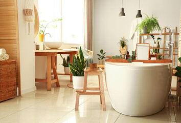 Interior of modern bathroom with bathtub, stepladder and houseplants