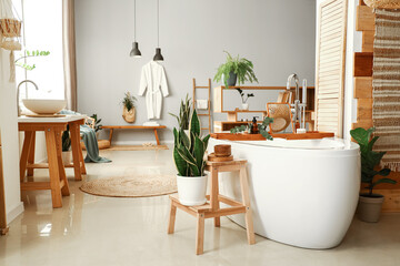 Interior of modern bathroom with bathtub, stepladder and houseplants