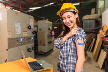 Asian young workers  pointing at his arm with a bandage after receiving the covid-19 vaccine.Vaccination for Essential Workers in healthcare at industrial factory.
