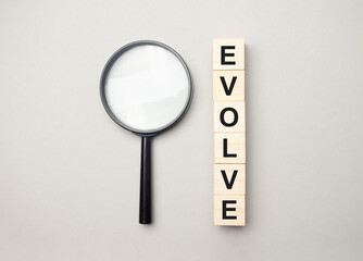 evolve word, text written on wooden cubes with stacks of coins of different heights on each cube on...
