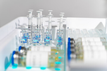 Syringes, vials and ampoules are neatly laid out in a special pallet for storing medical equipment, side view, close up, blurred foreground. Prepared treatment stuff in lab