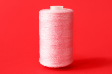 Fototapeta na wymiar Pink sewing thread spool on color background