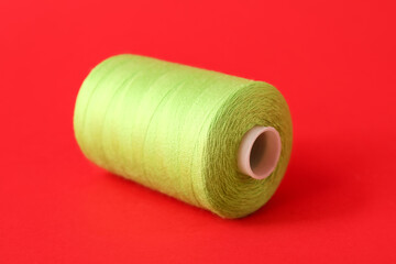 Fototapeta na wymiar Green sewing thread spool on color background