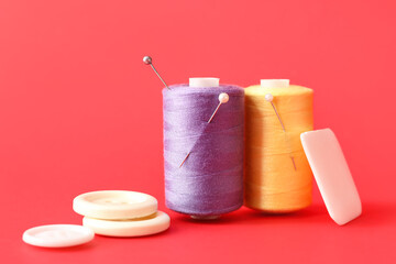 Sewing thread spools with pins, buttons and piece of soap on color background