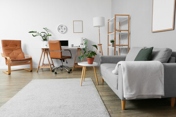 Interior of light room with modern workplace, shelf unit and sofa