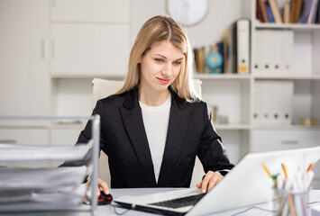Elegance young businesswoman sitting in office at workplace and working at laptop