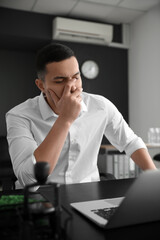 Worried young businessman working at table in office
