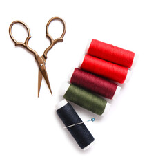 Thread spools with scissors and needle on white background
