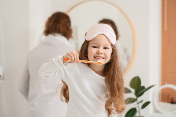 Little girl with sleeping mask brushing teeth in bathroom - Powered by Adobe
