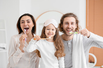 Little girl with her parents brushing teeth in bathroom