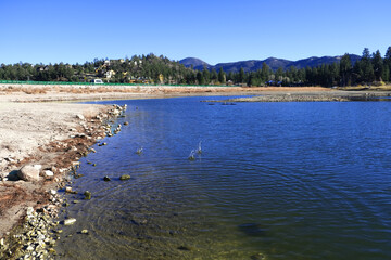 Beautiful images lake. Lake with sunlight lines dries trees under the blue sky.