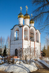 White bell tower with golden domes and a bright blue sky.