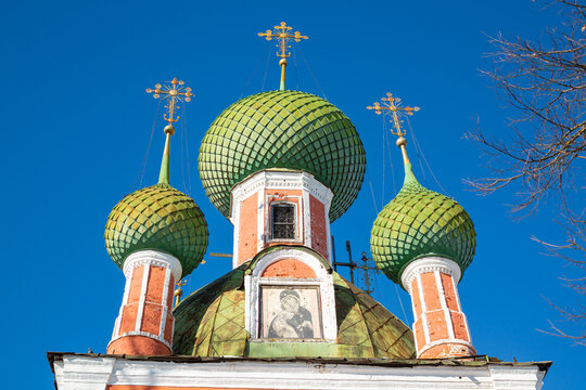 Lots of green domes of the church close-up against a bright blue sky.