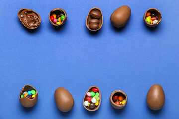 Delicious chocolate eggs with different fillings on blue background