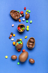 Delicious chocolate eggs with different fillings on blue background