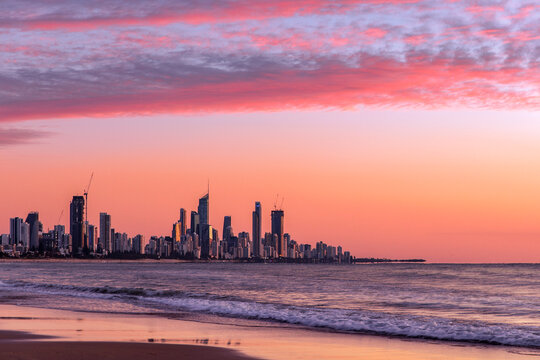 Pink clouds at sunrise over Surfers Paradise, Gold Coast. View from Burleigh beach - Powered by Adobe