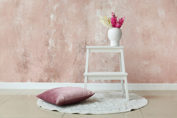 Stepladder stool with hyacinth flowers and pillow near color wall in room