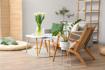 Interior of modern living room with sofa, table and daffodils in vase