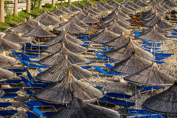 Sun umbrellas and sun beds on the empty beach in Saranda, Albania