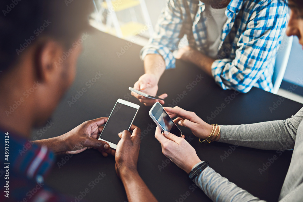 Poster Working hands-on with technology. Cropped shot of three people sitting around a table together and using their cellphones.