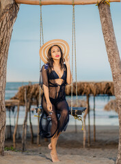 Beautiful Latina in swimsuit on a swing next to the beach in mexico