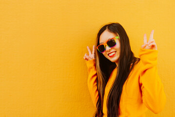 young asian woman in yellow sweater and sunglasses painted with lgbt pride rainbow flag making...