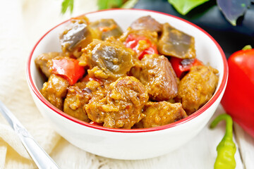 Meat with eggplant and pepper in bowl on board