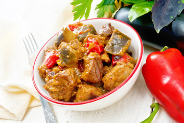 Meat with eggplant and pepper in bowl on table