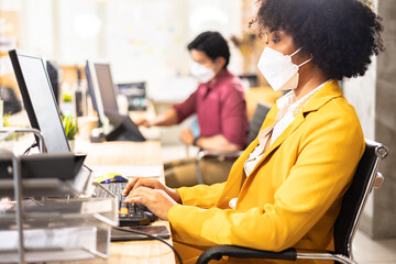 female African  coworkers team with face mask working in new normal office. COVID-19 protection by...