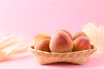 Peach fruit in basket on pink background