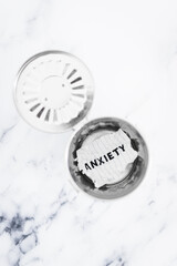 Anxiety text on torn page thrown inside trash bin, mental health concept