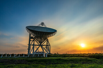 Astronomical radio telescope and beautiful sky clouds at sunset