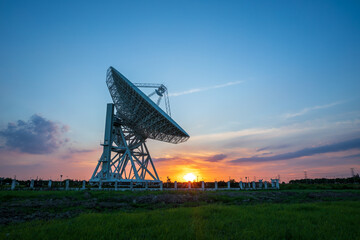Astronomical radio telescope and beautiful sky clouds at sunset