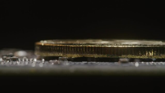 Side profile of a gold bitcoin rotating on a circuit board