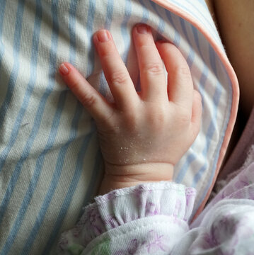M&atilde;o de um beb&ecirc; apoiado em sua m&atilde;e enquanto mama