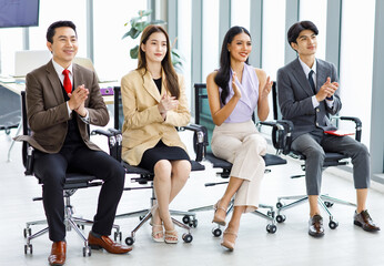 Asian young professional successful male and female businessmen and businesswomen group in formal business suit sitting side by side on chair in meeting room taking writing note in notebook together