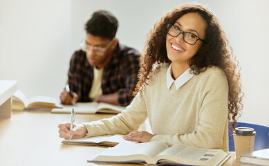 Taking notes. Cropped portrait of an attractive young female college student writing in her...