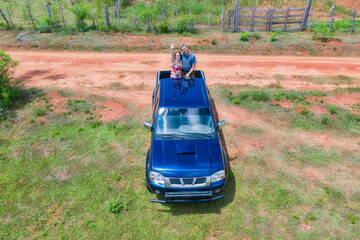 Aerial view of a woman and a man on the back of a pick-up truck in Paraguay with typical red sand...
