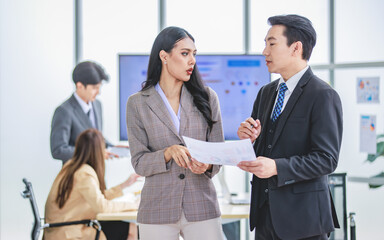 Millennial Asian professional successful male and female businessman businesswoman colleague in formal business suit standing holding report paperwork document discussing consulting for solution idea