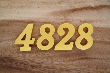 Golden Arabic numerals on a real brown and white wooden floor number 4828