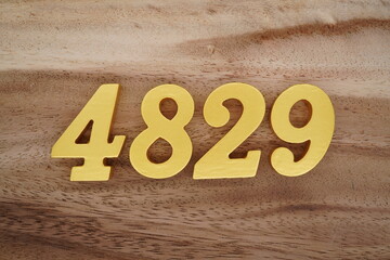 Golden Arabic numerals on a real brown and white wooden floor number 4829