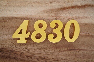 Golden Arabic numerals on a real brown and white wooden floor number 4830